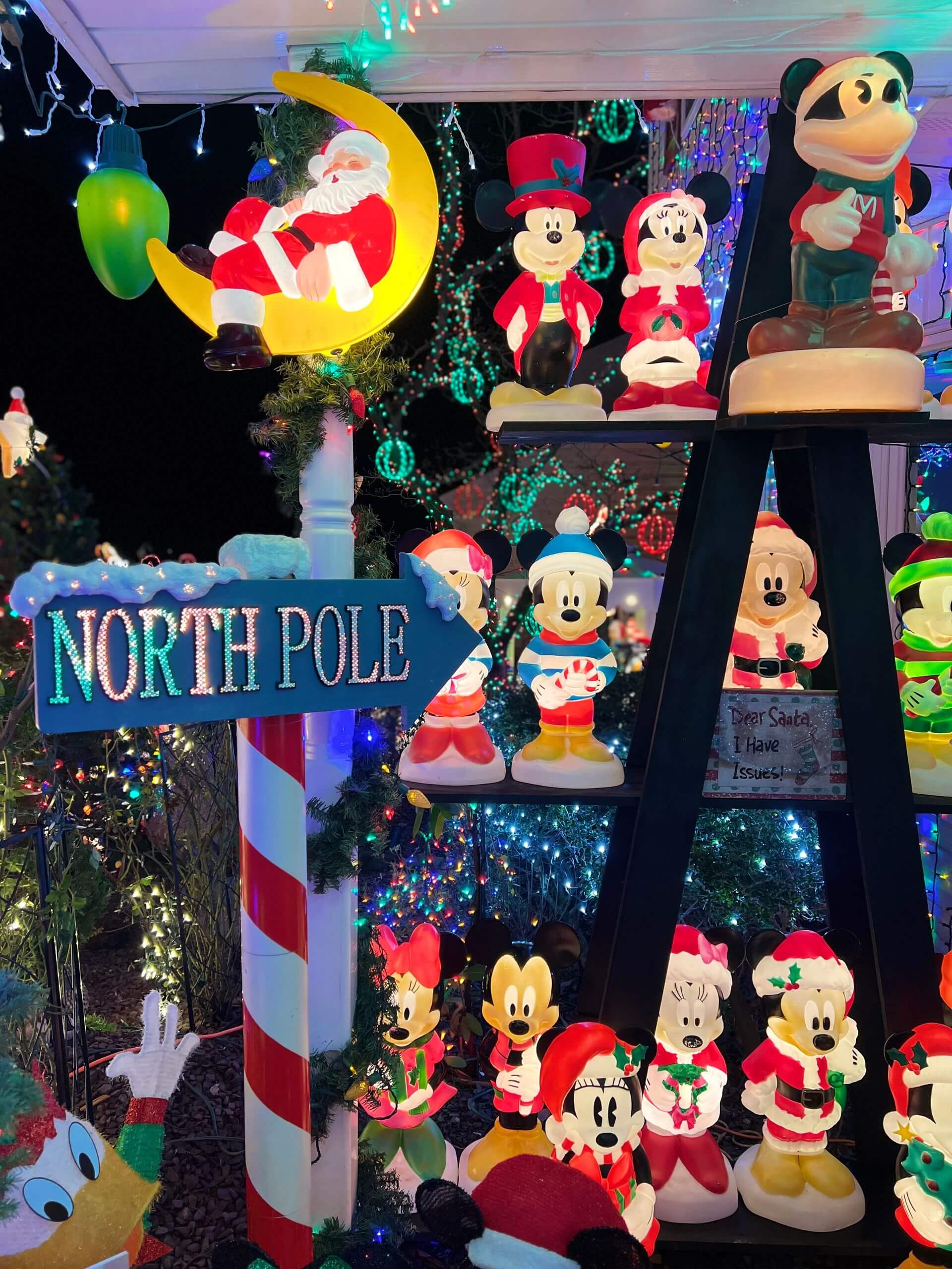 Bright and colorful Christmas decorations featuring Mickey Mouse and Santa at night.